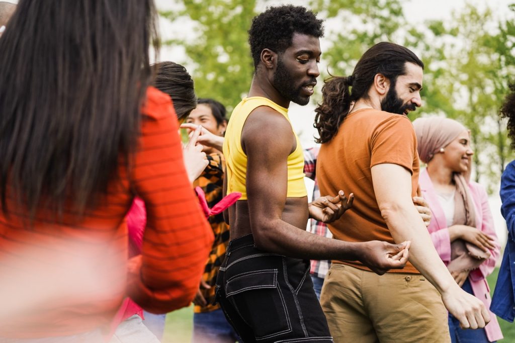 Young diverse people having fun outdoor dancing together - Focus on gay man wearing make-up